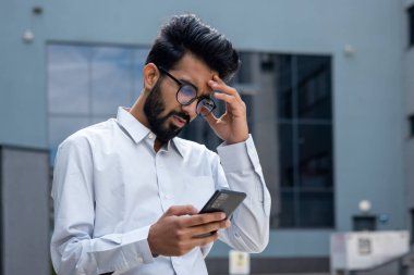 Ofis binasının dışında genç bir İspanyol işadamı, tişörtlü bir adam internette kötü haberler okuyor, telefondaki uygulamayı kullanıyor, bunalımlı adam başarı sonuçlarından memnun değil..