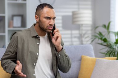 Kızgın genç Afrikalı Amerikalı adam evde telefonla konuşuyor. El kaldırır, sorunları çözer..
