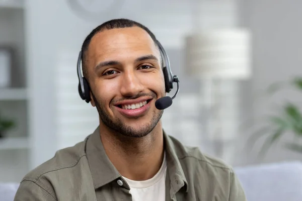 Close-up photo. Portrait of a young hispanic man at home wearing a headset looking at the camera and smiling.