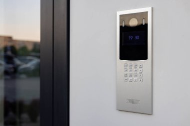 Doorbell with video camera and microphone, on the white wall of an apartment building, doorbell camera. clipart