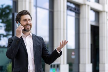 Olgun, başarılı bir patron telefonda konuşuyor. İş elbisesi giymiş kıdemli bir iş adamı. Müşterilerle akıllı telefon kullanıyor..