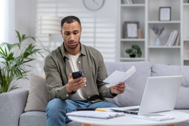 Belgelerle evde çalışan Afrikalı Amerikalı bir adam, evdeki koltukta oturup aldığı mektupları okurken, faturalara bakarken, sorunları çözmek için arayarak endişeleniyor..