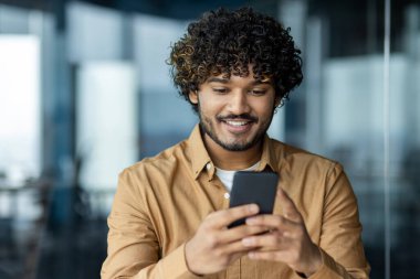 Genç işadamlarının internet başvurularını telefonla kullanmalarını, ofisteki bir adamın akıllı telefondan iyi haberler okumasını, Latin Amerikalı bir adamın mutlu bir şekilde gülümsemesini..