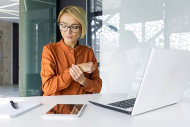 Ofis çalışanı kadının el eklemlerinde şiddetli ağrı var. İş yerindeki iş kadınlarında uzun süre çalışmak ve ofisin içinde dizüstü bilgisayarla çalışmak..