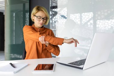 Ofis çalışanı kadının el eklemlerinde şiddetli ağrı var. İş yerindeki iş kadınlarında uzun süre çalışmak ve ofisin içinde dizüstü bilgisayarla çalışmak..