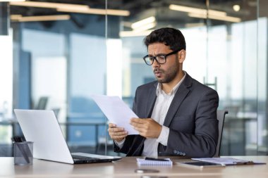 Yatırımcıların hesaplarını kontrol etmesi ve finansal raporları kontrol etmesi, işyerindeki başarılarından mutsuz ve hayal kırıklığına uğramış bir iş adamı..