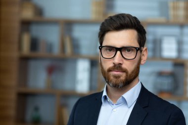 Yetişkin, deneyimli bir avukat, gözlüklü, ciddi bir adam klasik ofisin içinde, iş adamı kameraya bakıp düşünüyor..