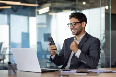 Başarılı iş adamının yakın plan portresi, kazanan telefon, iyi sonuçları kutlayan adam internetten iyi haberler aldı, ofisteki akıllı telefon uygulamasını kullanarak..