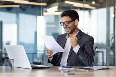 Arap yatırımcı, kazanan el ele tutuşuyor, işyerindeki işadamı ofis içi kağıt işlerinde çalışıyor, raporlara bakıyor, mali başarı sonuçlarından memnun..