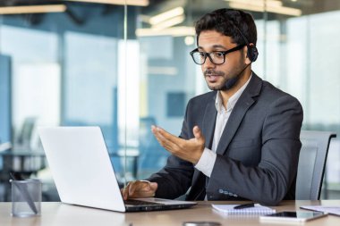Ciddi konsantre olmuş ve düşünen bir iş adamı. Kulaklıklı bir iş adamı bilgisayarındaki web kamerasına bakıyor. Takım elbiseli patron, iş arkadaşları ve ortaklarıyla gizlice konuşuyor..