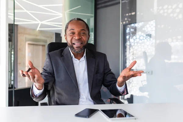 Video call online meeting, african american businessman boss smiling and looking at camera, man in business suit mature having fun talking with colleagues, on virtual meeting inside office remotely.