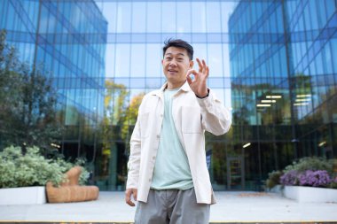 Ofis binasının önünde gülümseyen ve kendinden emin bir Asyalı 'nın portresi..