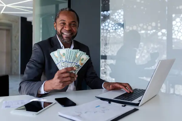 노트북에서 사무실에서 아프리카계 사업가의 초상화와 현금을 카메라에 — 스톡 사진
