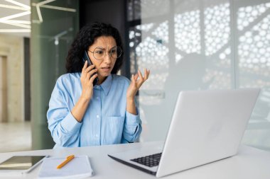 Ofisin içinde sinirli ve sinirli bir kadın patron, hayal kırıklığına uğramış bir iş kadını telefonda konuşuyor, ofisteki İspanyol bir kadın, iş yerinde dizüstü bilgisayar kullanıyor..