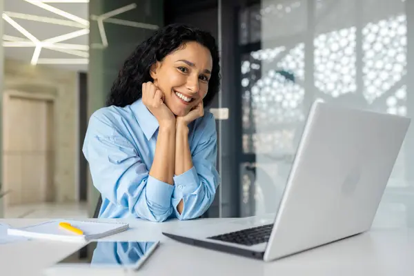 stock image Portrait of young beautiful business woman inside office at workplace with laptop, smiling successful hispanic woman smiling and looking at camera, satisfied female boss in shirt sitting at table.