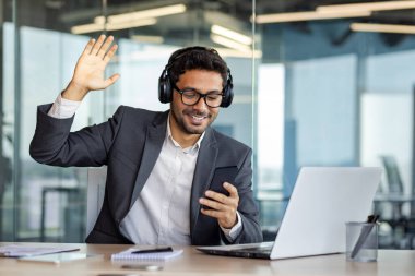 Genç, neşeli iş adamı ofiste dinleniyor, kulaklıklı adam müzik dinliyor, şarkı söylüyor ve dans ediyor, telefonda uygulama kullanıyor, elinde akıllı telefonuyla çalışıyor..
