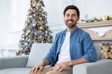 Mutlu bir gencin portresi. Evdeki kanepede güven içinde oturuyor. Yılbaşı tatili beklentisi ve beklentisiyle..