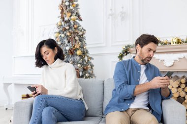 Genç bir çift, bir erkek ve bir kadın, evlerinde kanepede farklı taraflarda oturuyorlar ve telefon kullanıyorlar. Yılbaşı tatillerinde, ilişkilerine ve kutlamalarına kayıtsız kalarak kavga ettiler..