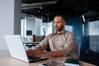 İşyerinde çalışan ciddi konsantre bir adam, iş adamı dizüstü bilgisayarda daktilo kullanıyor, programcı yeni yazılım geliştiriyor..