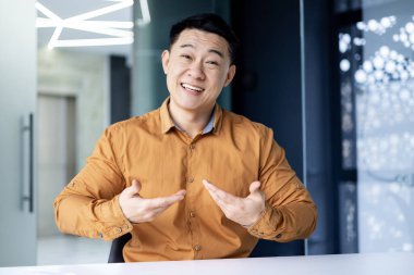 Mutlu başarılı iş adamı web kamerasından izliyor, meslektaşlarıyla uzaktan konuşan gülümseyen bir adam bilgisayardaki video çağrısını kullanıyor, ofisteki Asyalı adam.