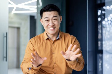 Mutlu başarılı iş adamı web kamerasından izliyor, meslektaşlarıyla uzaktan konuşan gülümseyen bir adam bilgisayardaki video çağrısını kullanıyor, ofisteki Asyalı adam.