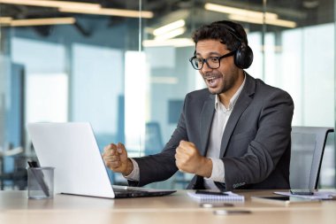 Ofisteki işyerinde bir adam spor maçı izliyor, kulaklıklı bir iş adamı ve laptopuyla işyerinde tezahürat yapıyor, neşeli bir patron, zaferi kutluyor, gülümsüyor..