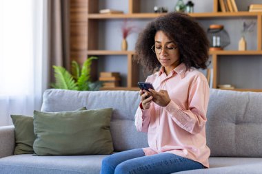 Ciddi düşünen bir kadın evde oturmuş telefonda konuşuyor. Kıvırcık telefonlu İspanyol kadın mesaj yazıyor. Düşünüyor, internet sayfalarını okuyor, sosyal ağları kuruyor..