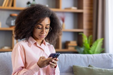 Ciddi düşünen bir kadın evde oturmuş telefonda konuşuyor. Kıvırcık telefonlu İspanyol kadın mesaj yazıyor. Düşünüyor, internet sayfalarını okuyor, sosyal ağları kuruyor..