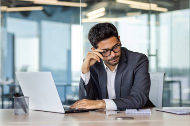 Yorgun erkek ofis çalışanı masamda dizüstü bilgisayarın önünde oturuyor, çok fazla çalışmaktan, yorgunluktan, baş ağrısından,.