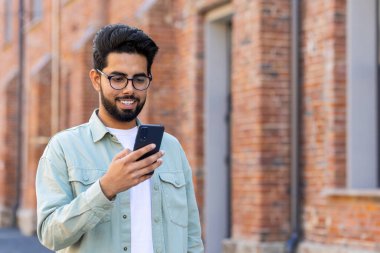 Genç bir adam elinde telefonuyla şehirde dolaşıyor, günlük giysiler içindeki bir işadamı akıllı telefondan başvuru kullanıyor, gülümsüyor, online sayfalar okuyor, mesaj yazıyor..