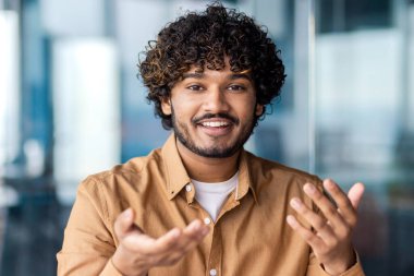 Webcam görüntüsü, çevrimiçi video görüşmesi, gülümseyen adam konuşuyor ve kameraya bakıyor, iş yerindeki iş adamı iş yerinde iş arkadaşlarıyla konuşuyor..