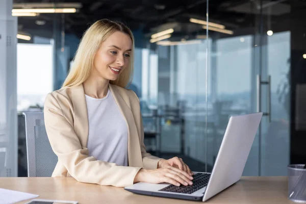 stock image Young beautiful business woman working inside office with laptop, female worker satisfied with results smiling, sitting at table, successful woman reading screen data close up.