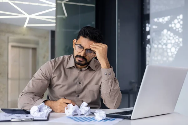 Businessman disappointed sad depressed sitting among crumpled documents papers inside office at workplace, man not satisfied with achievement results, bad financial reports, unhappy accountant.