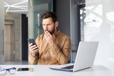 Telefonla kötü haber okuyan adam, iş yerinde elinde akıllı telefon tutan işadamı, bilgisayarla ofisin içinde şok olmuş ve hayal kırıklığına uğramış..