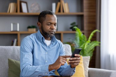 Evdeki koltukta oturan olgun bir adamın elinde telefon tutan, oturma odasındaki sinemada mesaj okuyan, akıllı telefondaki uygulamayı kullanan kıdemli Afro-Amerikan bir adamın ciddi düşünceleri..