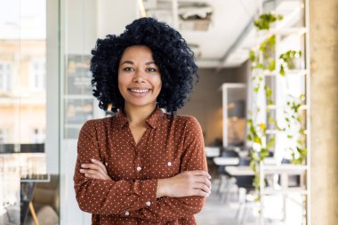 Genç, kendinden emin bir Afrikalı Amerikalı kadının portresi, yönetmen ve yemek şirketi ve restoranın kurucusu, kollarını kavuşturarak kameranın önünde duruyor..
