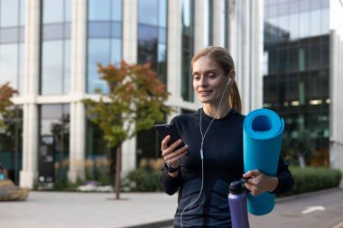 Neşeli kadın antrenmana gidiyor, yoga minderli sporcu online flört uygulaması ve ortak eğitim kullanıyor..