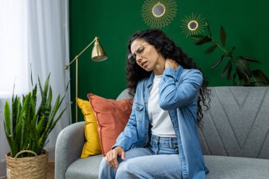 Kanepede oturan bir kadın boynunu tutarken muhtemelen rahatsızlık ya da acı hissediyordu.