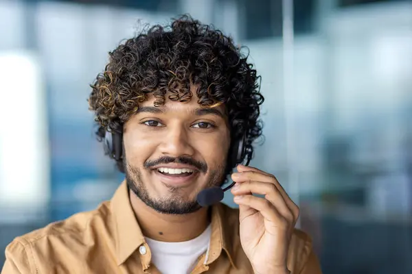 Web camera view, online video call, young man smiling and looking into camera with headset phone for video call, businessman inside office, selling and advising consumers, support service.