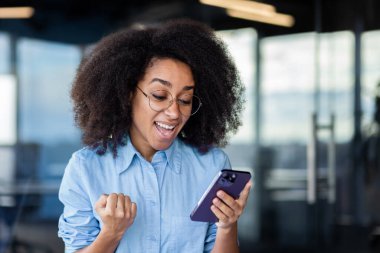 İş yerindeki neşeli iş kadını zafer ve başarılı başarı elde etti. Çevrimiçi olarak zafer ve zafer haberi aldı..