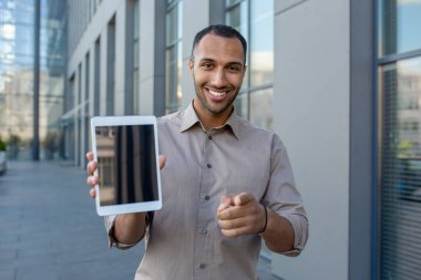 Kendine güvenen işadamı size bakıyor ve bir tablet ekranı gösteriyor. Bağlılık, bağlılık ve modern teknolojiyi ima ediyor..