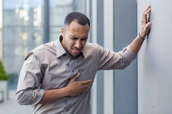 Man experiencing chest pain outdoors, clutching his heart in distress, concept of heart attack, health emergency
