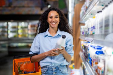 Markette alışveriş yaparken elinde süt şişesi olan neşeli bir müşteri..