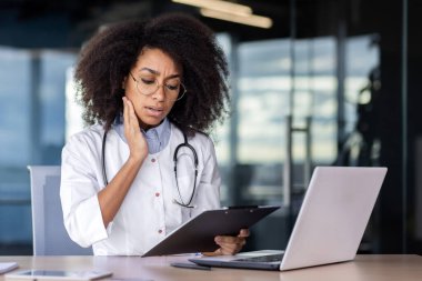 Hayal kırıklığına uğramış İspanyol kadın terapist elinde kağıtlarla panoya bakıyor ve endişeleniyor. Steteskoplu kadın hemşire analiz sonuçlarını kontrol ediyor ve endişelerini dile getiriyor..