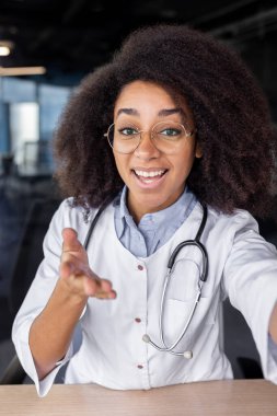 Kadın Afrikalı Amerikalı doktorun modern akıllı telefonu kullanırken görüntülü görüşme yaptığı ilk kişi. Çekici terapist özel başvuru ve gülümseme yoluyla online danışmanlık sağlıyor.