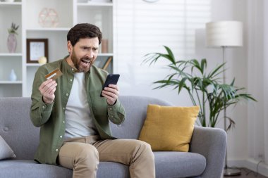 Evdeki oturma odasındaki koltukta oturan, elinde banka kartı ve telefonu olan, reddedilmiş para transferi, negatif denge, dolandırıcılık para kaybı.