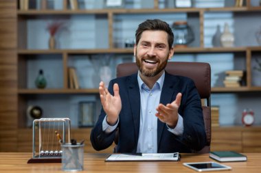 Tatmin olmuş erkek, kahverengi deri koltukta tablet ve sarkacıyla otururken kapalı alanda el çırpıyor. Mutlu şirket başkanı, dişlek gülüşlü meslektaşının verimli işini alkışlıyor ve övüyor..