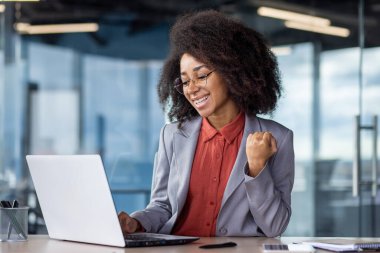 İş yerindeki iş kadını başarılı sonuçlar elde etti. Dizüstü bilgisayarlı kadın çalışan zaferi kutluyor, el ele tutuşuyor, iş yerindeki takım elbiseli kadın iş yerinde..