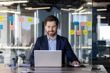 İşyerinde başarılı bir iş adamı, dizüstü bilgisayarda yazı yazan patron, gülümseyen, satış raporlarını hazırlayan finansör, iş yerindeki tecrübeli yatırımcı..