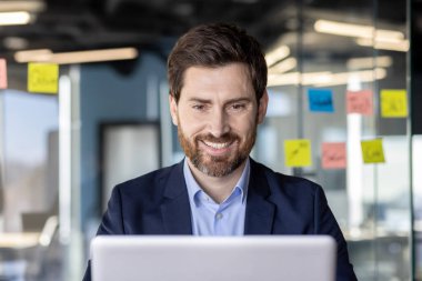 İşyerinde başarılı bir iş adamı, dizüstü bilgisayarda yazı yazan patron, gülümseyen, satış raporlarını hazırlayan finansör, iş yerindeki tecrübeli yatırımcı..